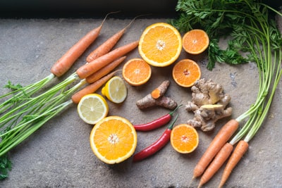 Beside the orange slice fruit green and orange vegetables
